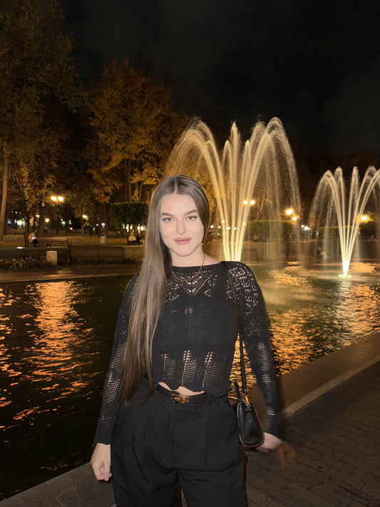 Street style photo, Fashion look, Casual-chic outfit, White corset top, Black wide-leg pants, Elegant jewelry, Designer bag, European architecture background, Evening light, Summer/Spring collection.