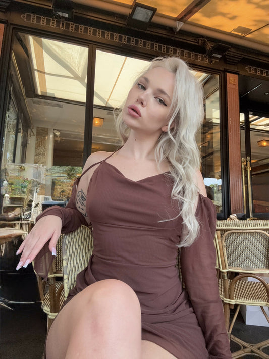 Elegant café photoshoot in Paris. Blonde model wearing a chocolate brown off-shoulder dress, sitting at a classic French bistro. Romantic, feminine and sophisticated aesthetic with soft natural lighting — ideal for fashion, lifestyle or beauty branding.