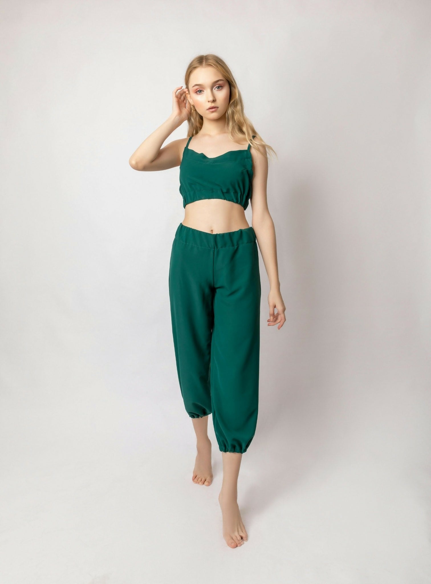 Full-body portrait of a young blonde woman wearing a green matching outfit. Studio photo with clean white background, ideal for virtual try-on, fashion brands, or digital catalogs. Tags: standing pose, hands visible, minimalistic, casual fashion, trendy,