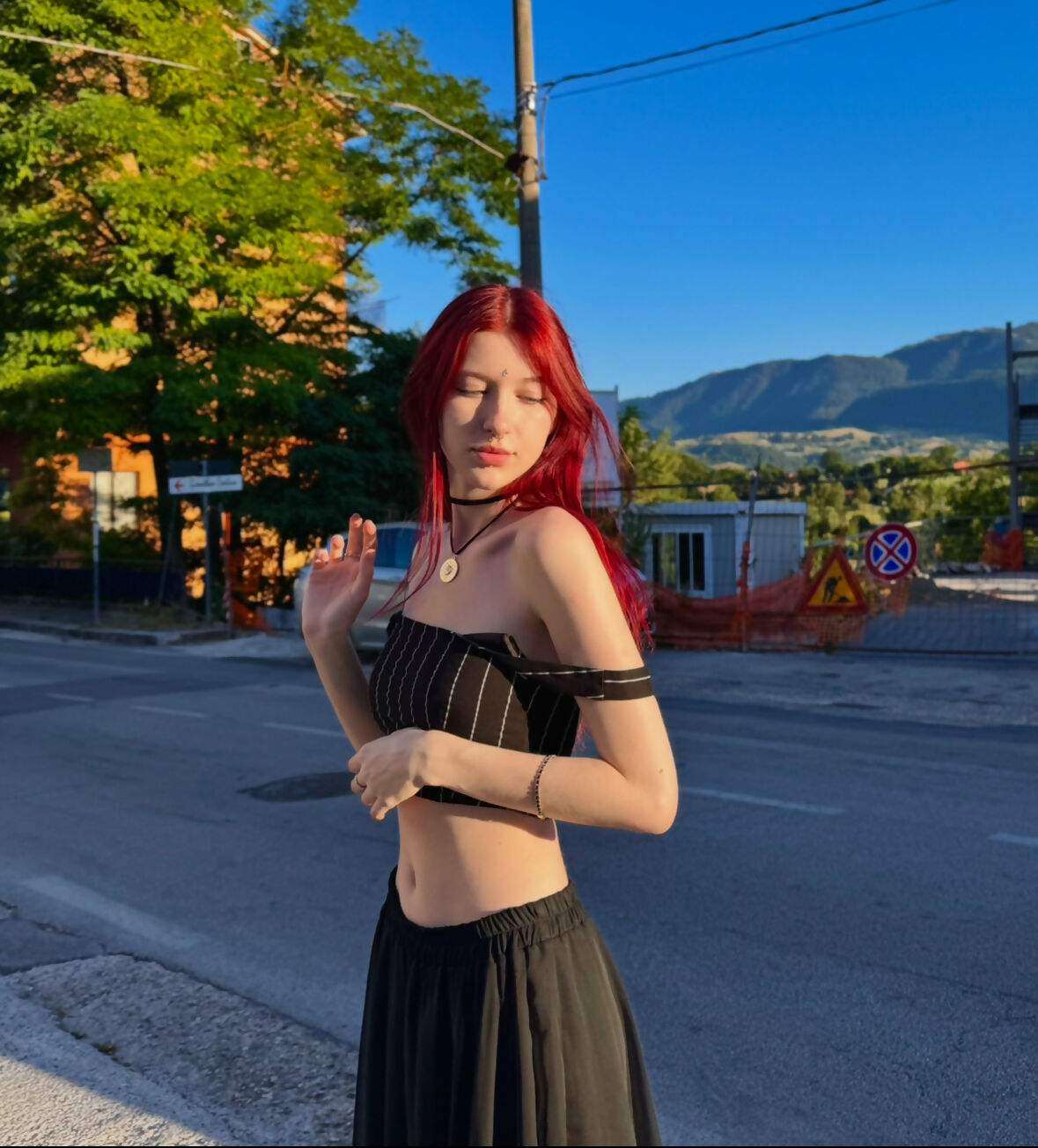 a girl with red hair is standing on the street